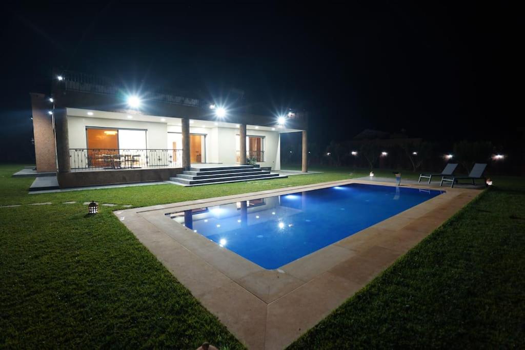 a swimming pool in front of a house at night at Villa Écologique à Proximité de la Plage in Agadir