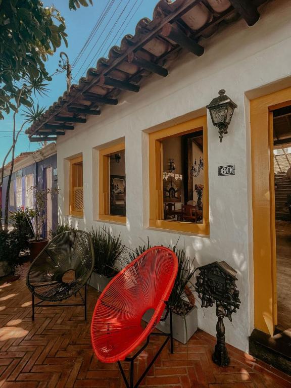 a patio with two red chairs and a house at Casa Amada in Arraial d'Ajuda