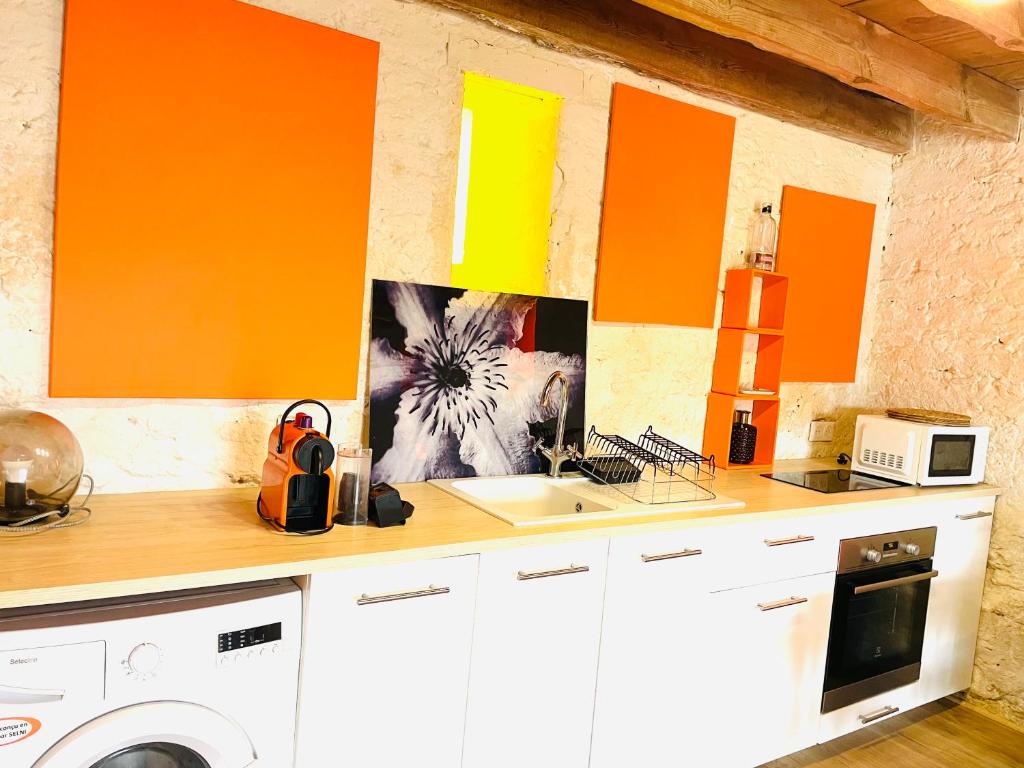 una cucina con pareti arancioni e gialle e un lavandino di L'annexe St Armand - À 2 pas de la l'Eyre - a Salles