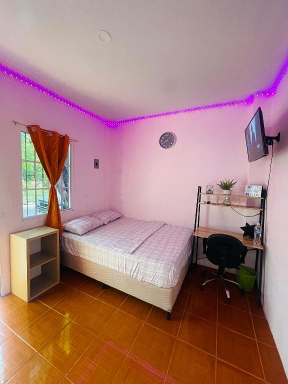 a bedroom with a bed and a desk and pink lights at Hostal Mónaco in San Miguel
