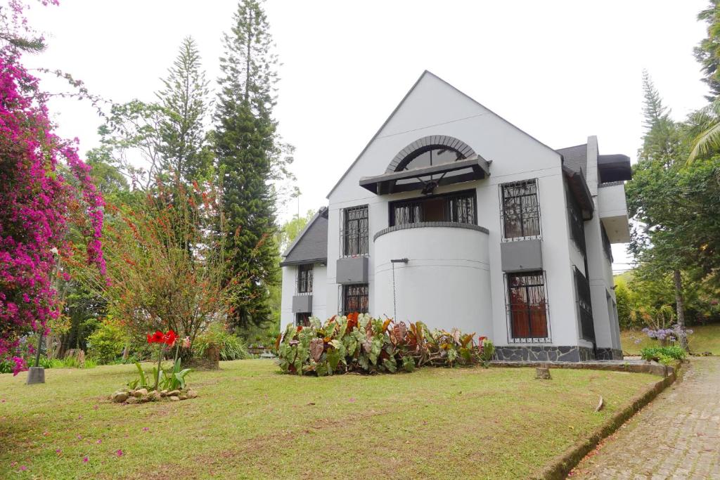 a white house with flowers in the yard at Hermosa Finca El Castillo - Excelente Ubicación Rionegro Marinilla in Rionegro