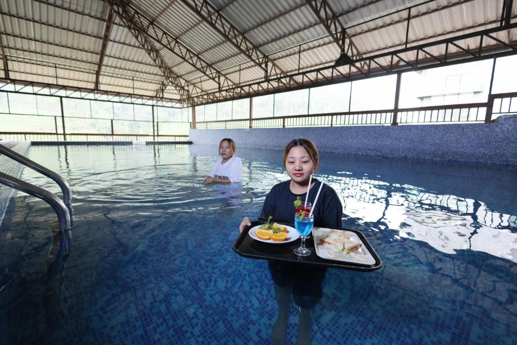 een vrouw met een dienblad eten in een zwembad bij Misty Gate in Vythiri