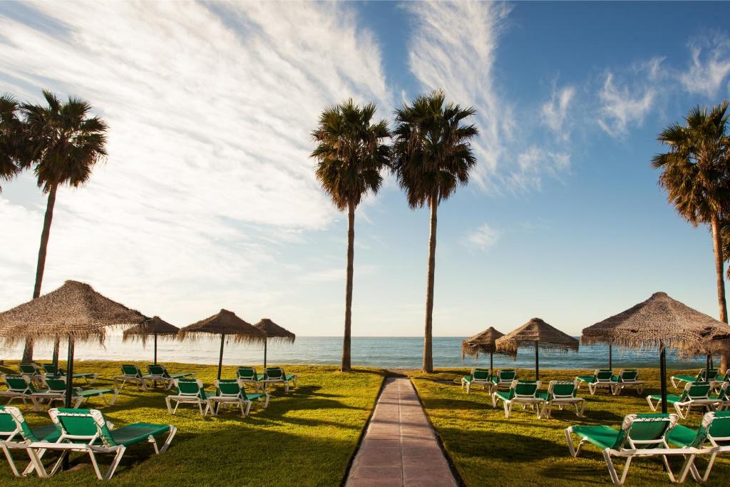 a path leading to the beach with chairs and palm trees at Ona Marinas de Nerja Spa Resort in Nerja
