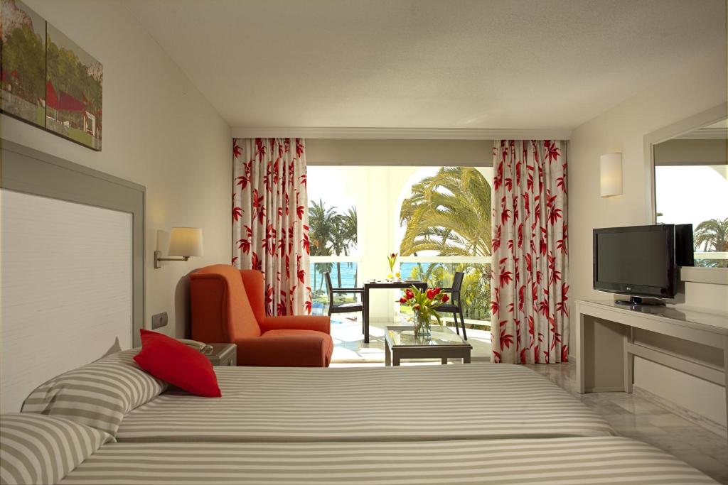 a bedroom with a bed and a television and a chair at Ona Marinas de Nerja Spa Resort in Nerja