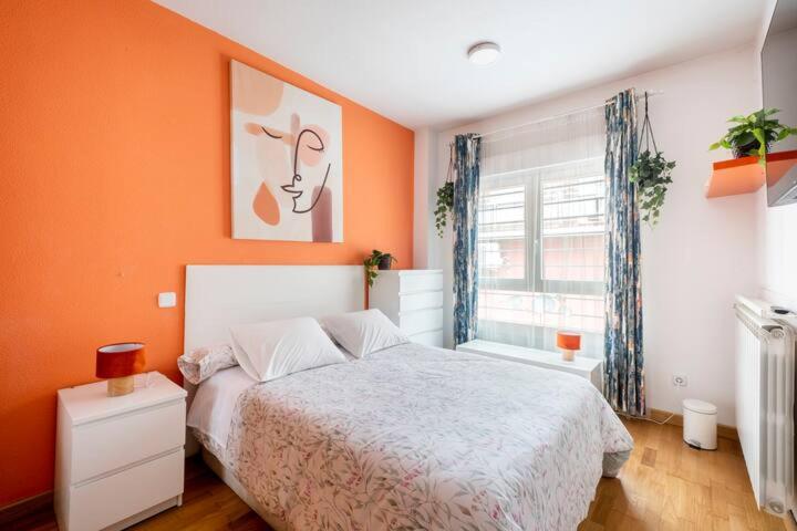 a bedroom with orange walls and a bed and a window at ESPECIAL para GRUPOS a 3 paradas del metro Atocha in Madrid