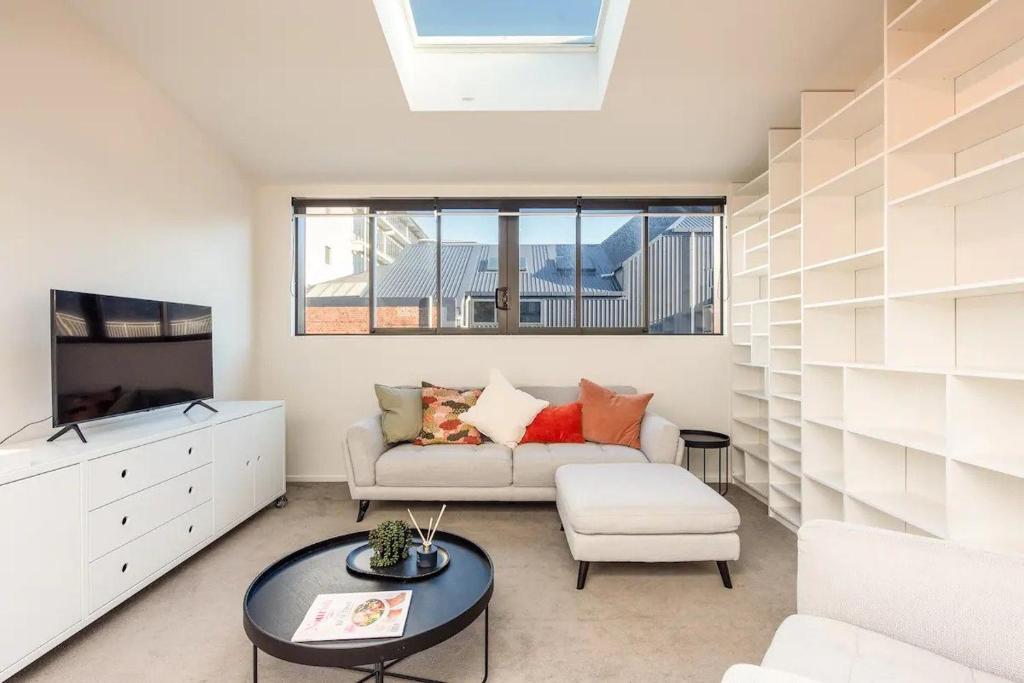 ein Wohnzimmer mit einem Sofa und einem TV in der Unterkunft Inner City Apartment in Wellington