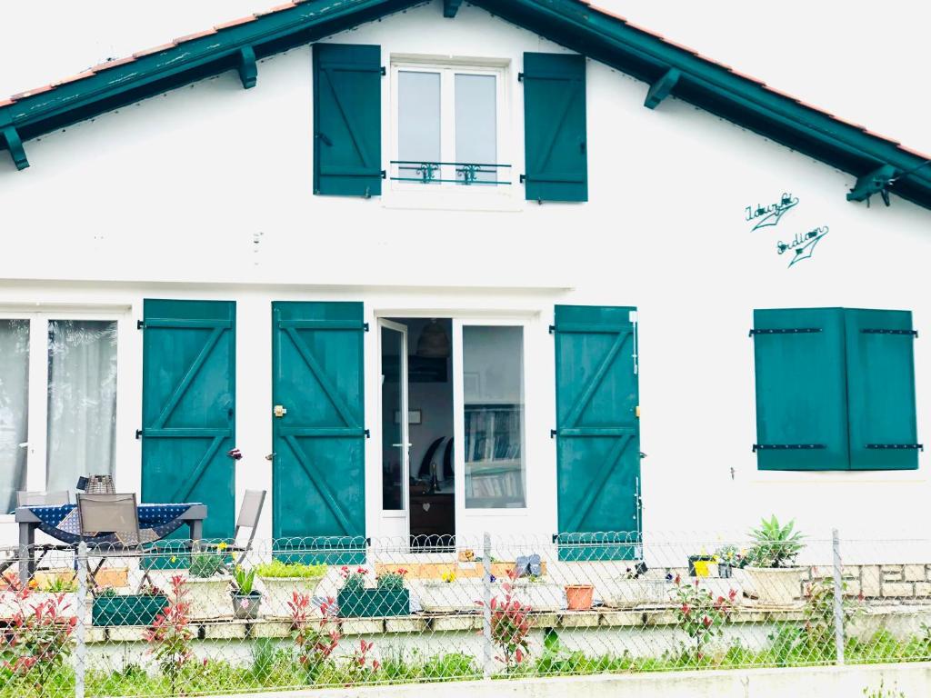 ein weißes Haus mit grünen Türen und einer Terrasse in der Unterkunft La terrasse à Erromardie in Saint-Jean-de-Luz