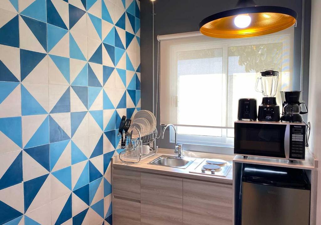 A small kitchen run places a sink and dishware beneath a bright window beside the main appliance stack.