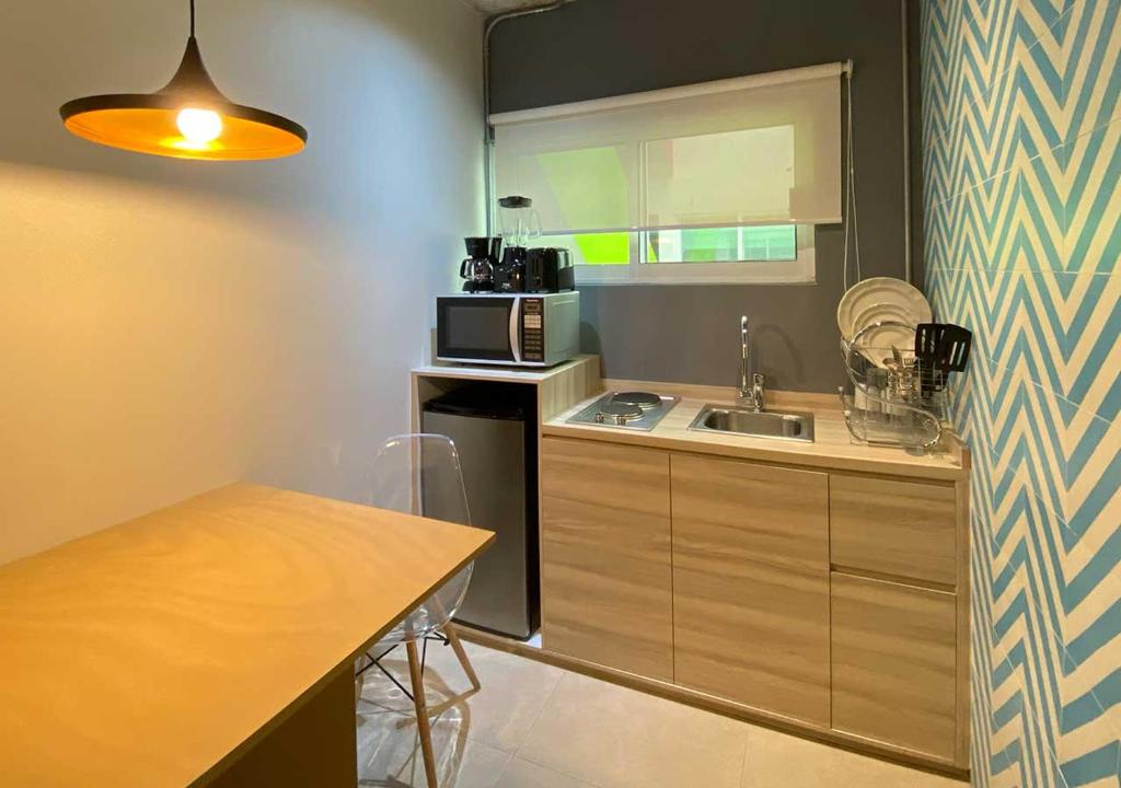 A compact kitchenette pairs a sink, microwave, refrigerator, and dining table.