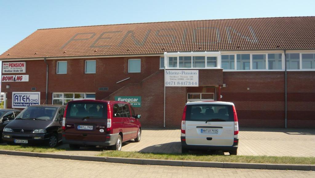 three cars parked in a parking lot in front of a building at Müritz-Pension Waren in Waren