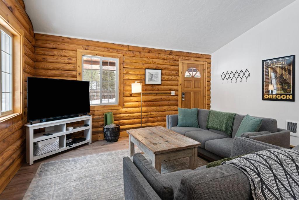 a living room with a couch and a tv at Pine Loop Log Cabin in La Pine