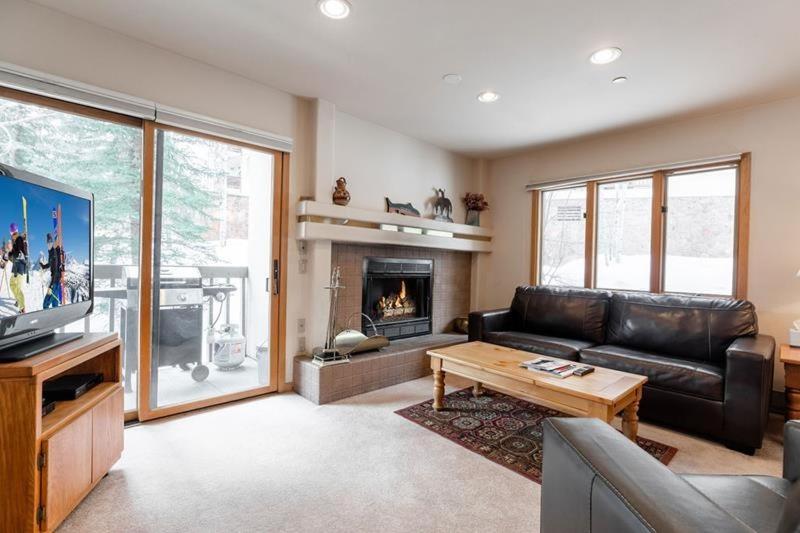 a living room with a leather couch and a fireplace at Townsend Place Ski In Ski Out Access in Beaver Creek