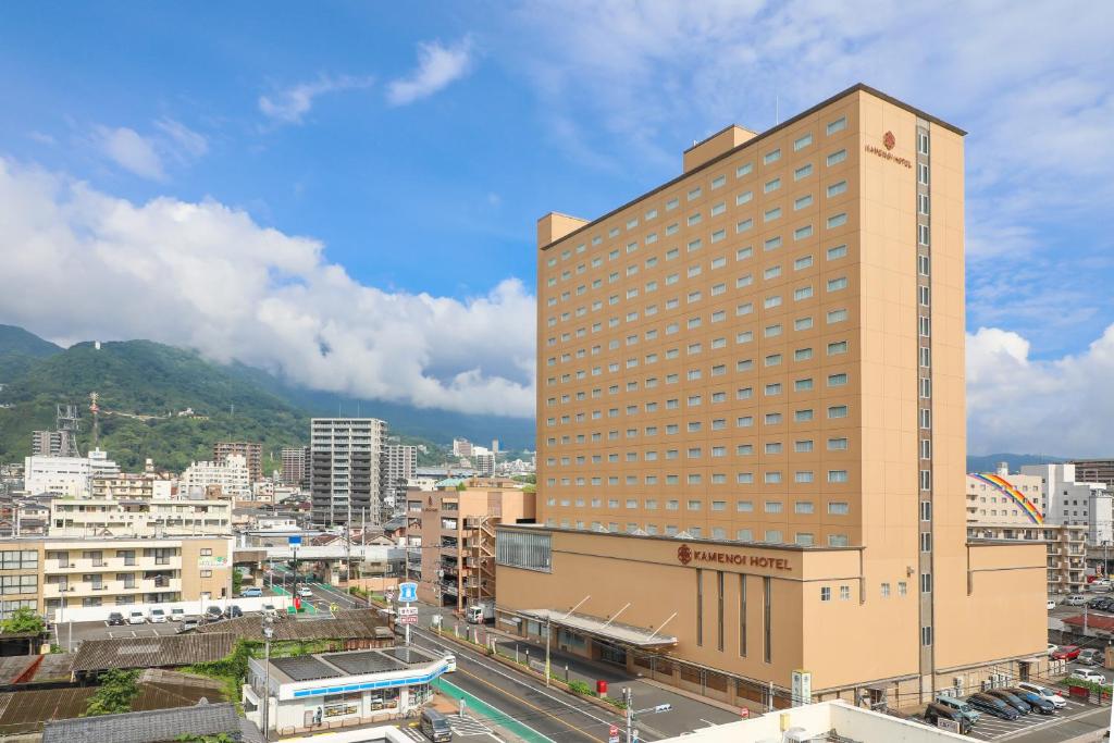 un edificio alto en una ciudad con una montaña en KAMENOI HOTEL Beppu, en Beppu