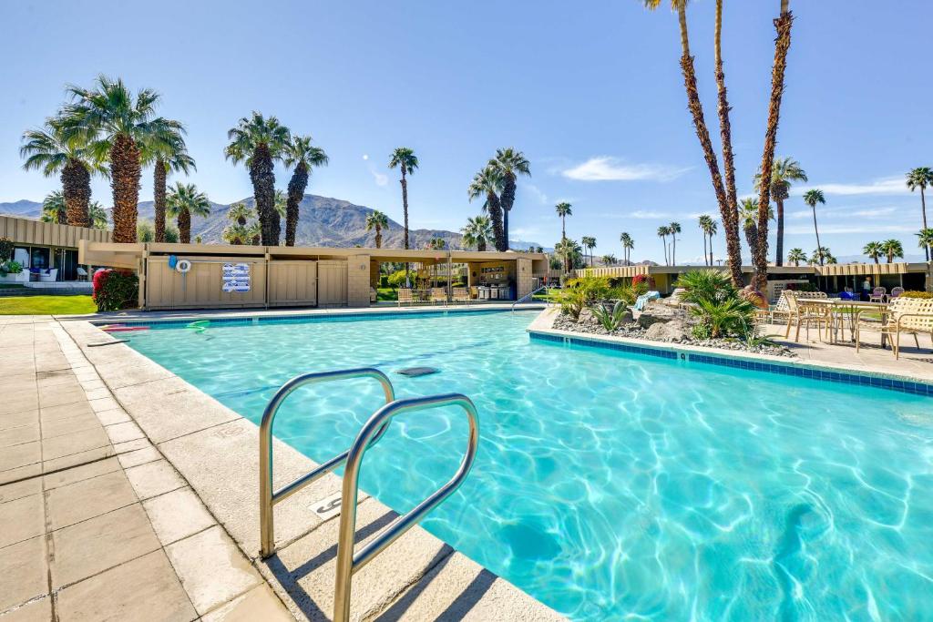 a swimming pool with palm trees and a building at Mid-Century El Paseo Condo in Iconic Sandpiper! in Palm Desert
