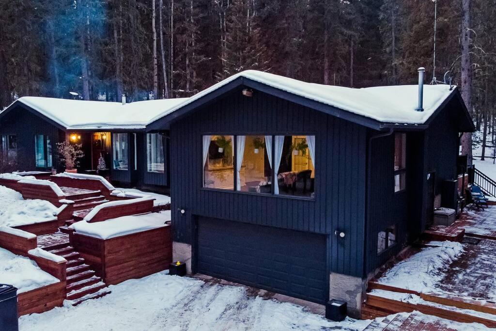 a blue cabin with snow on the roof at Awesome family vacation home in Bragg Creek in Bragg Creek
