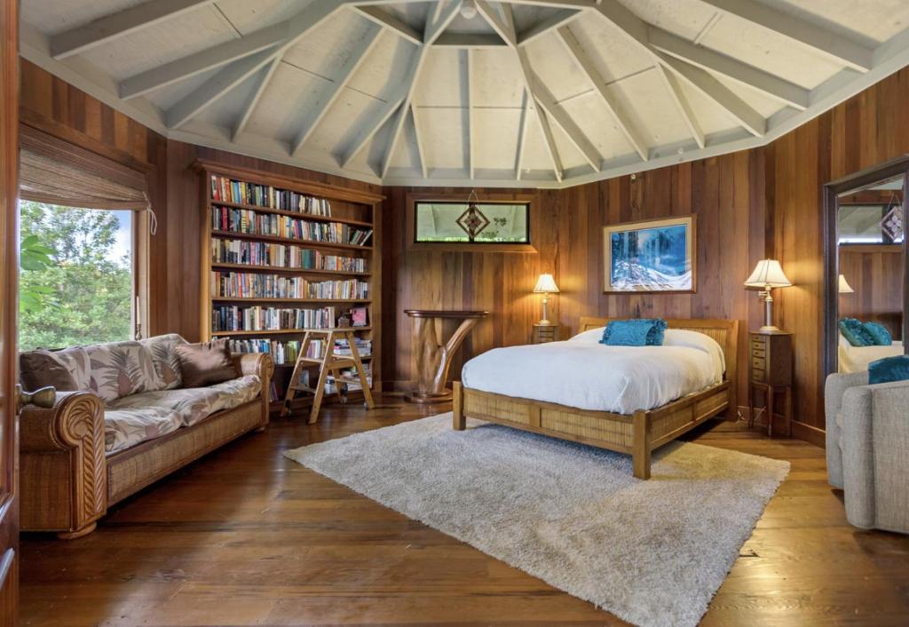 a bedroom with a bed and a couch and book shelves at Kula Ohana in Captain Cook