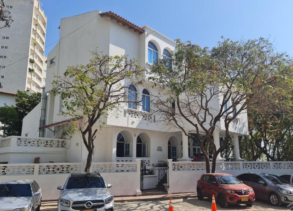 a white house with cars parked in front of it at Casa Blanca del Mar in Santa Marta