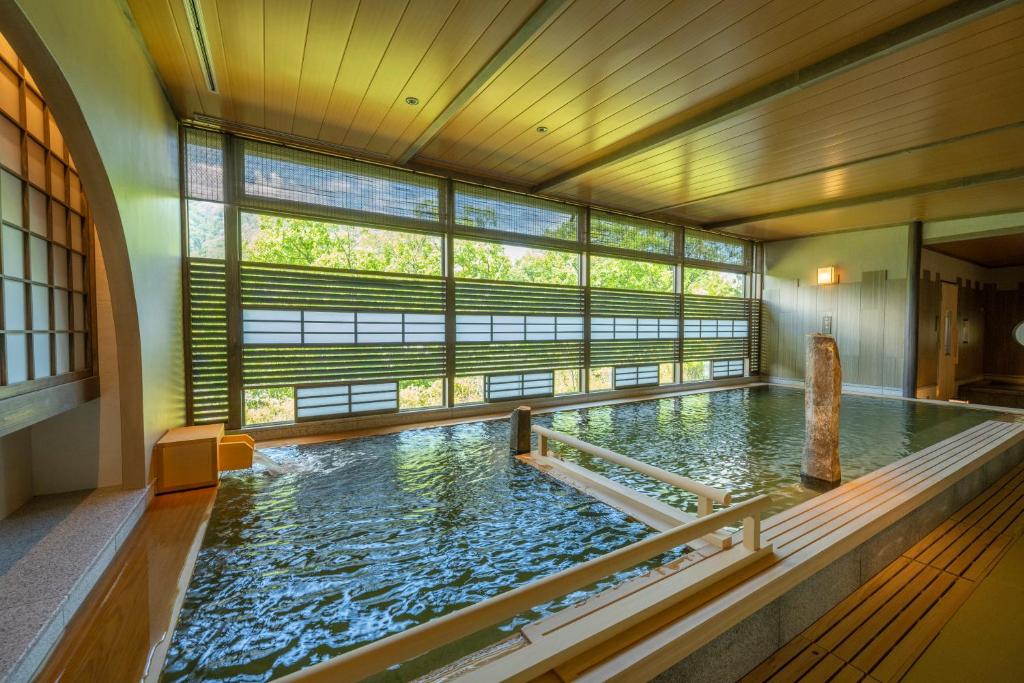 Una gran piscina de agua en una habitación con ventana en Jozankei Onsen Yurakusoan, en Jozankei