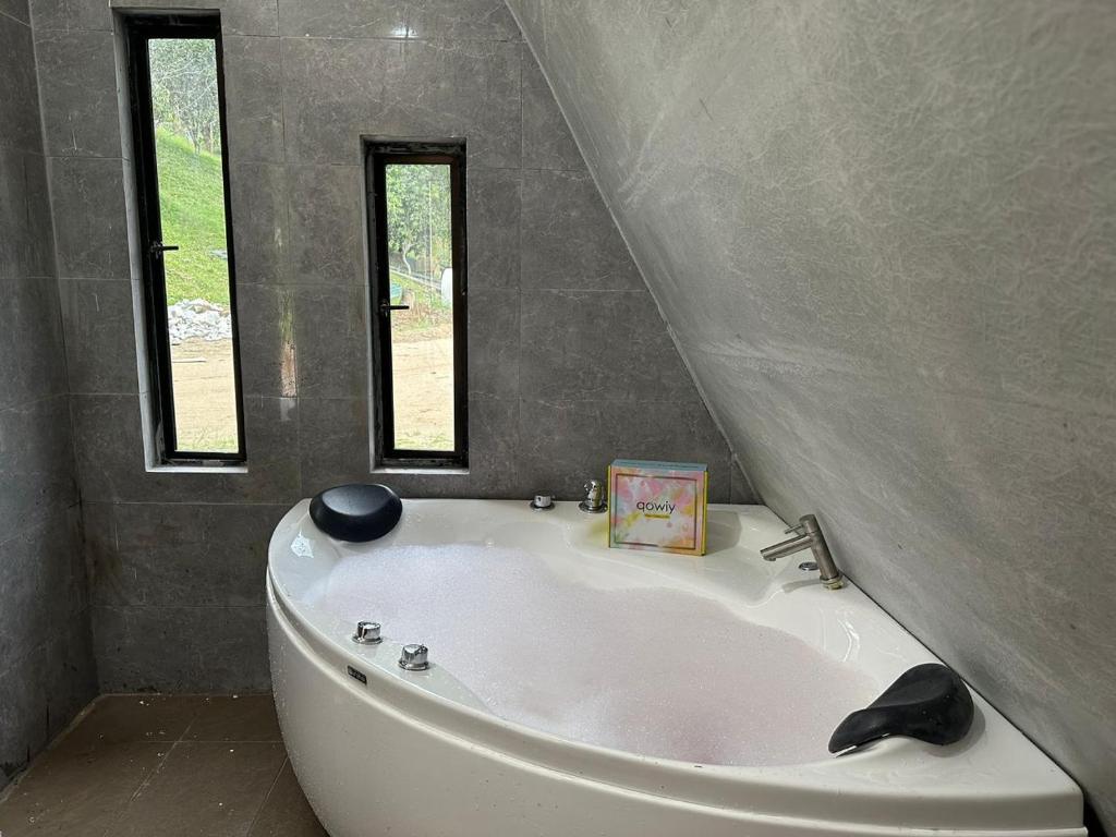 a white bath tub in a bathroom with two windows at Qowiy Village Langat in Hulu Langat