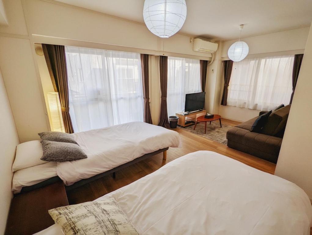 東京にあるAmber Iidabashi - Vacation STAY 90436vのベッド2台とソファが備わる小さな客室です。