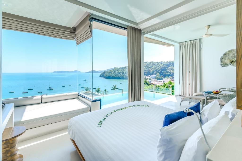 a bedroom with a large window overlooking the ocean at Bandara Villas, Phuket in Panwa Beach