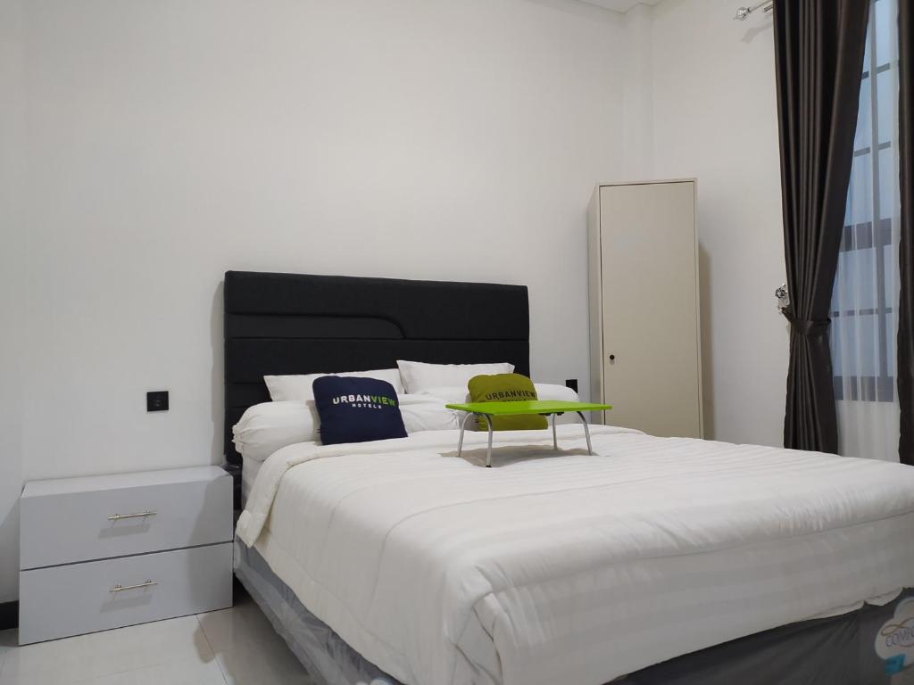 Un dormitorio con una cama grande y una mesa verde. en Urbanview Badran Residence Syariah Manahan en Solo