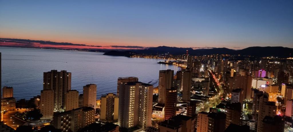 uma vista de uma cidade à noite com a água em Cielo de Benidorm em Benidorm