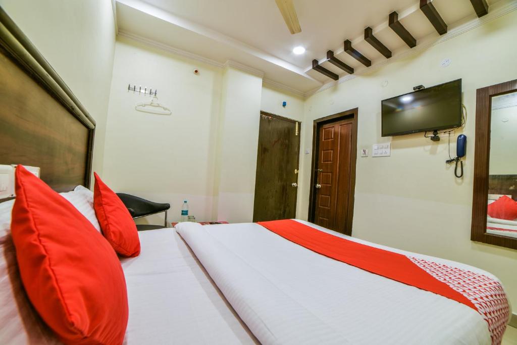 1 dormitorio con 1 cama con almohadas rojas y TV en OYO Surya Teja Residency, en Khammam