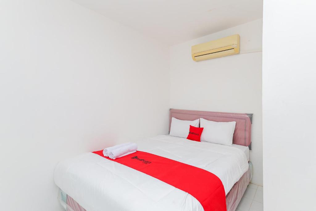 a bedroom with a white bed with a red blanket at RedDoorz near Pasar Lama Serang in Serang