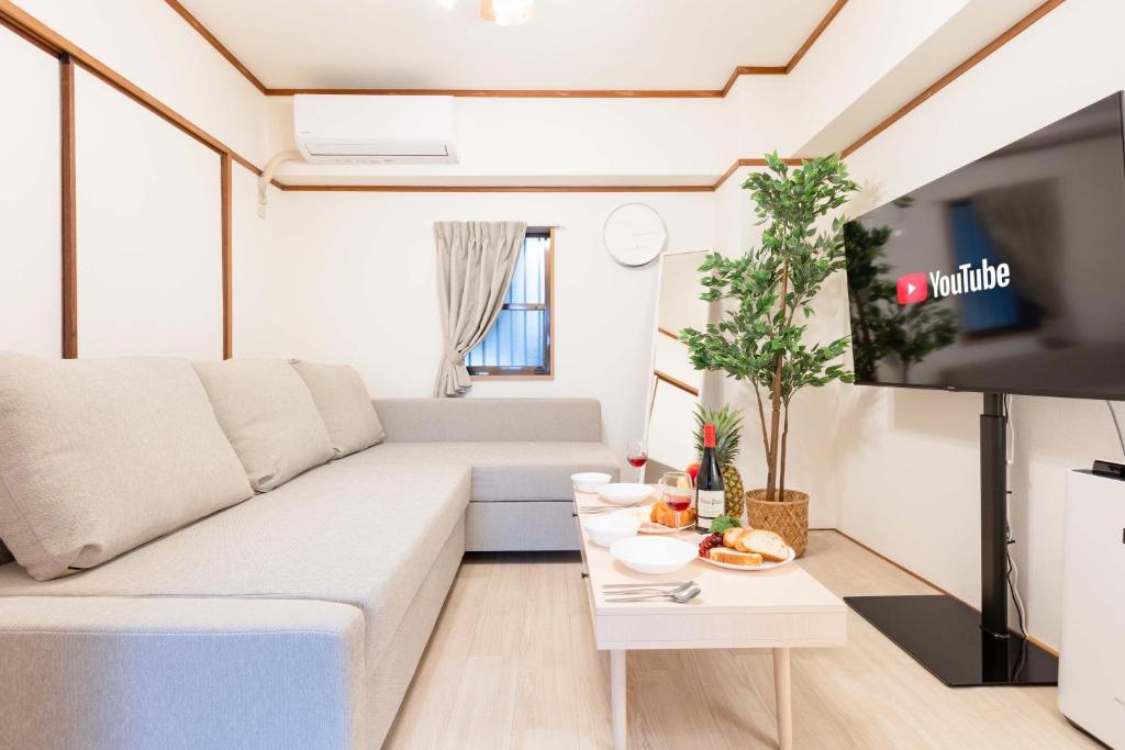 uma sala de estar com um sofá branco e uma televisão em River Side Namba 600 em Osaka
