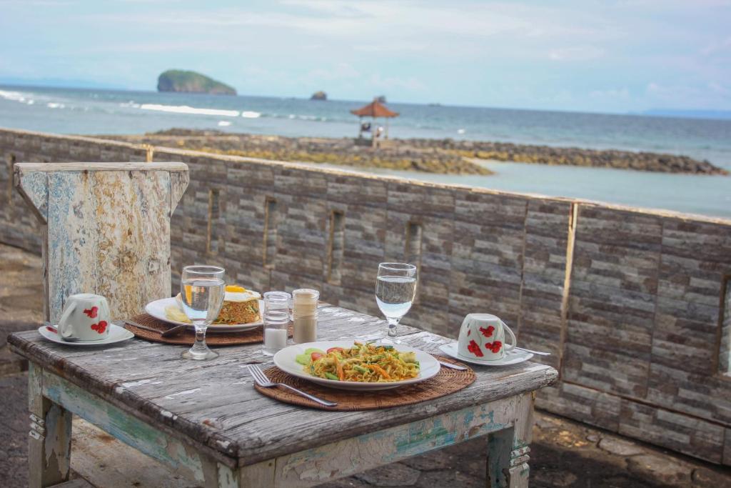een tafel met een bord eten op het strand bij Temple Cafe & Cottages in Candidasa