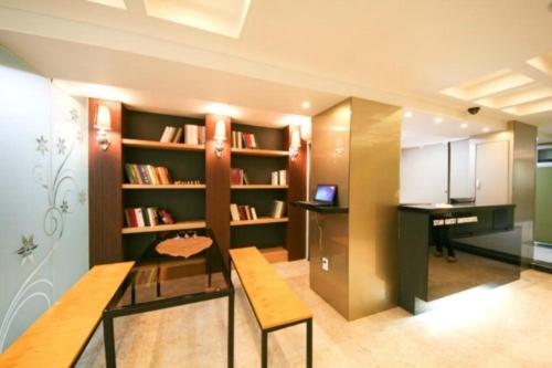 a room with a table and a desk and bookshelves at Star Guest House in Seoul