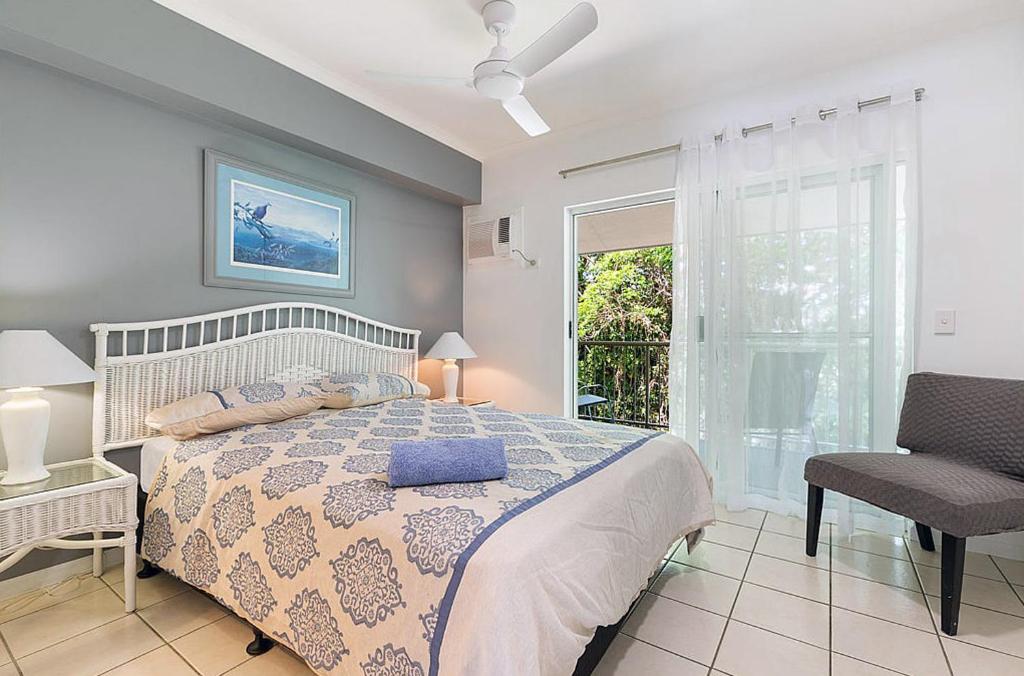 1 dormitorio con 1 cama, 1 silla y 1 ventana en Lovely Spacious 2 Bedroom 2 Bathroom Townhouse in Resort, en Port Douglas
