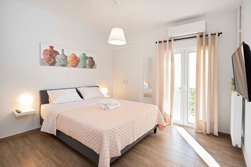 a white bedroom with a bed and a television at Filoxenia MG city center in Athens