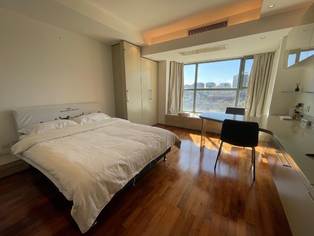 Schlafzimmer mit einem Bett, einem Tisch und einem Fenster in der Unterkunft Beijing Elegant Seasons Park Apartment in Peking