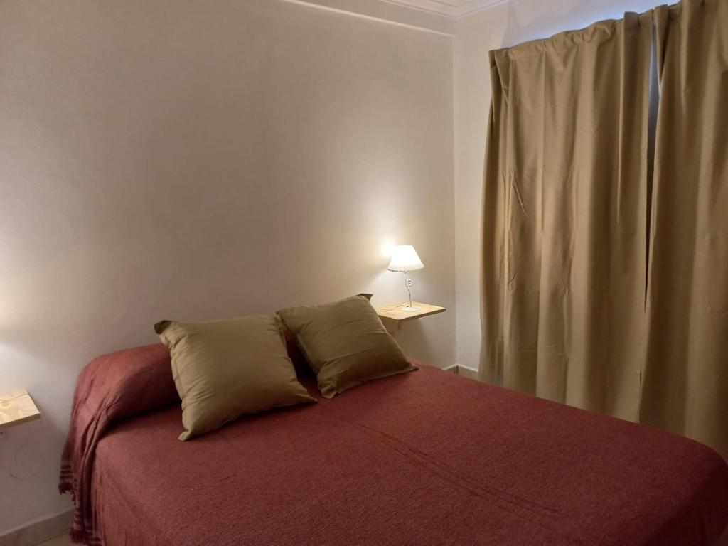 a bedroom with a bed with a red blanket and a window at Departamentos Centro Dpto 2 1 habitacion in Tandil