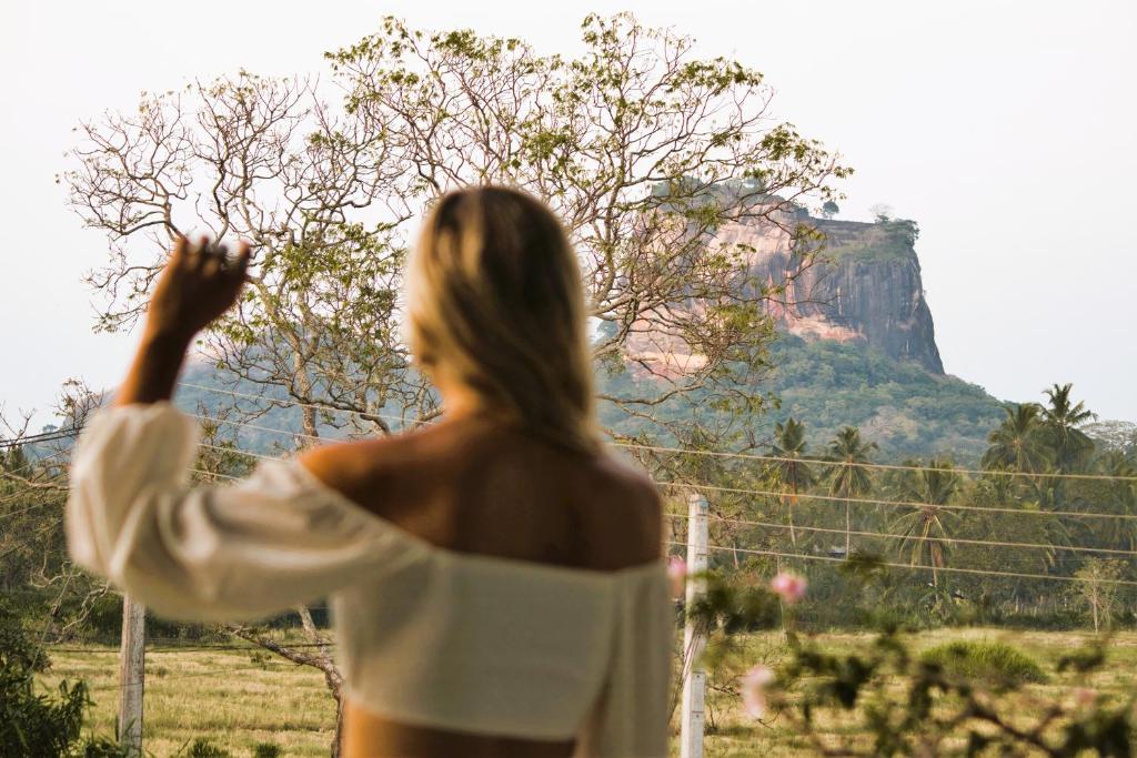 Una donna con un asciugamano che guarda fuori da una finestra di Royal Rock Sigiriya a Sigiriya