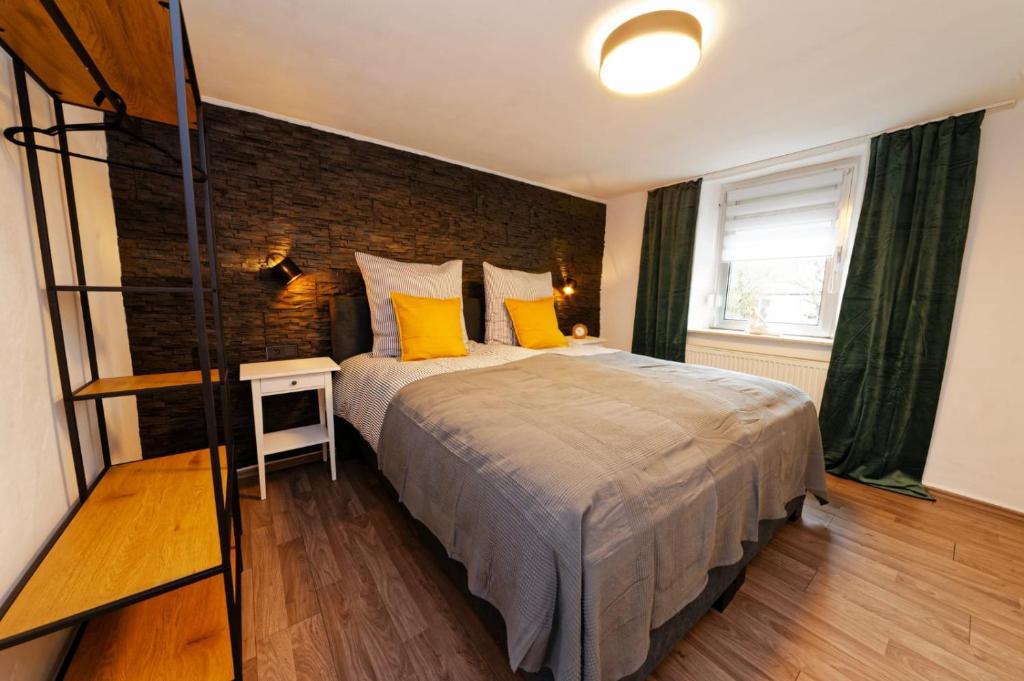 a bedroom with a large bed and a brick wall at Casa Eifel in Beilingen