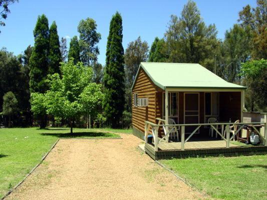 Cabaña pequeña con techo verde en un campo en Sandy Hollow Tourist Retreat, en Sandy Hollow