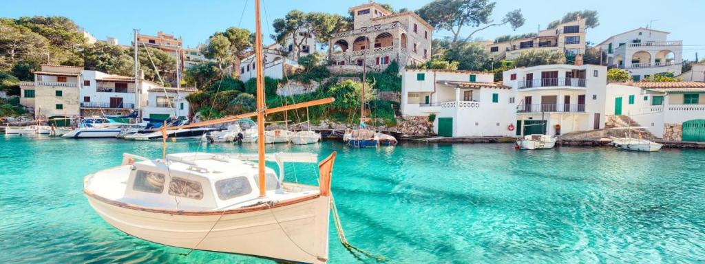 un barco está atracado en un puerto con casas en Hotel Santanyi Port, en Cala Figuera