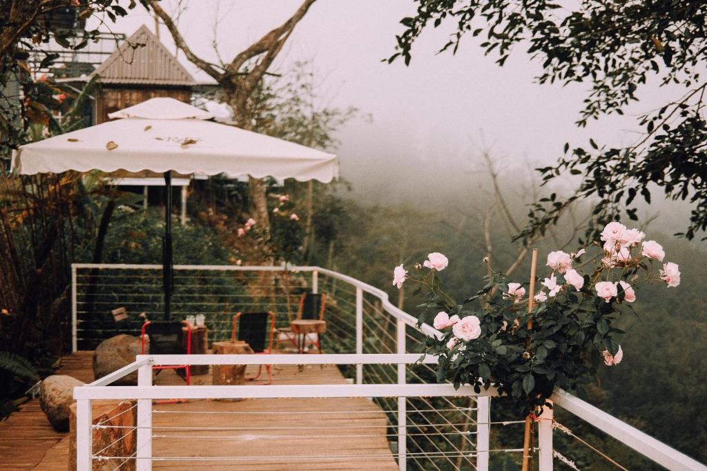 a wooden walkway with a gazebo and pink roses at Retro Khe Sanh in Lao Bao