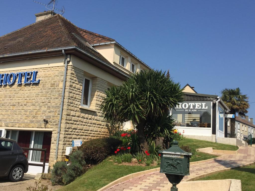 un bâtiment avec une horloge devant lui dans l'établissement Hotel du 6 juin, à Sainte-Mère-Église