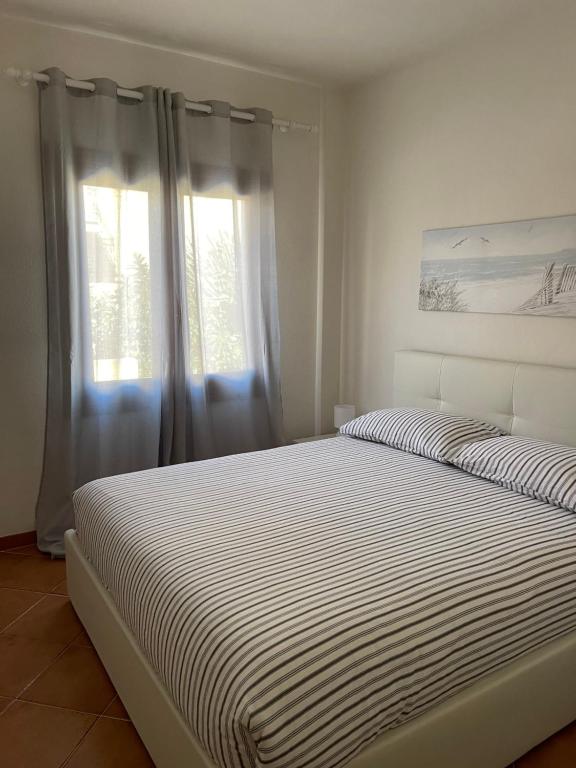 Dormitorio blanco con cama y ventana en Casa Fiorella - Vista Mare, en Palau