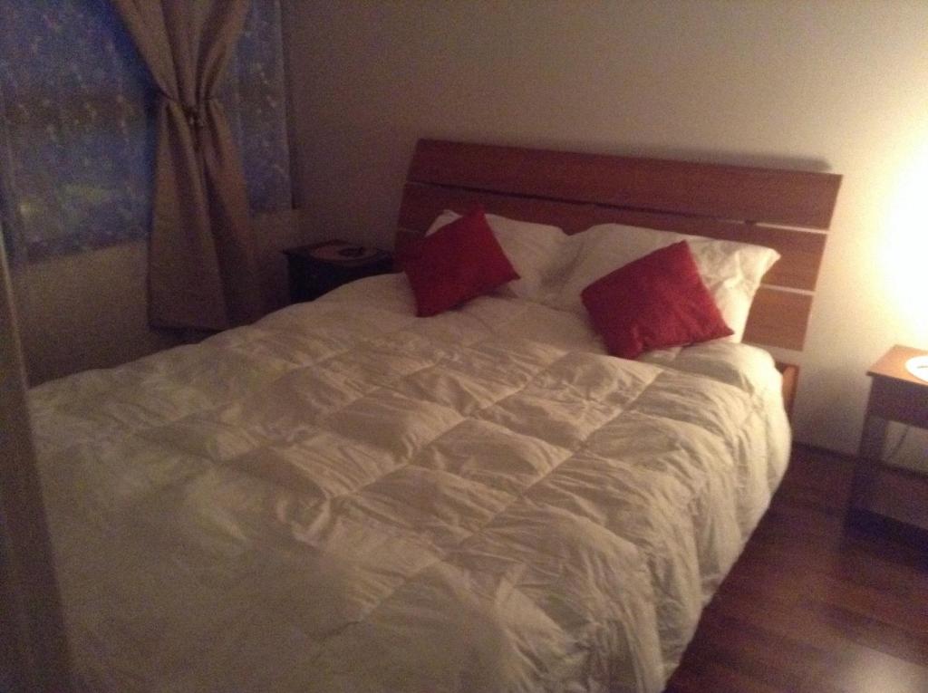 a bedroom with a white bed with two red pillows at Capital in Santiago