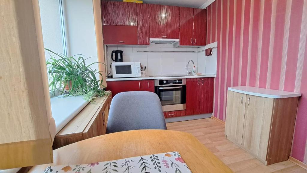 una pequeña cocina con armarios rojos, mesa y silla en Sporta 2, en Daugavpils