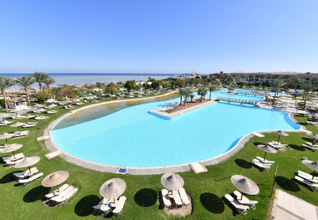 an overhead view of a large swimming pool with lounge chairs and the ocean at JAZ Aquamarine in Hurghada