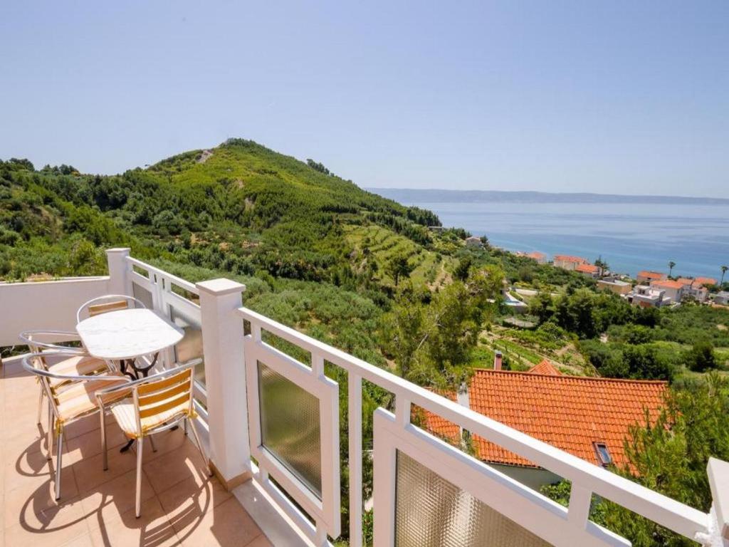 balcone con tavolo, sedie e vista sull'oceano di Apartments Bandalo a Podstrana