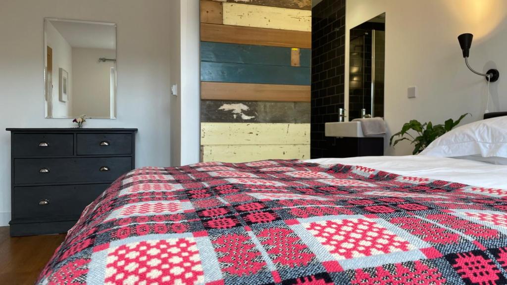 a bedroom with a bed with a red and white quilt at 1 Woodlands in Llandysul