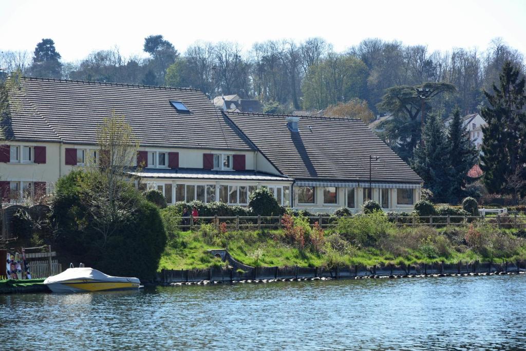 dom na brzegu rzeki z łodzią w obiekcie Logis Hôtel des Lacs Paris Sud w mieście Viry-Châtillon