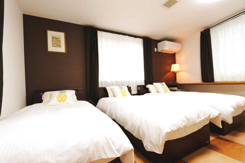 2 camas en una habitación con sábanas blancas en 東京昭島迎賓館A, en Akishima
